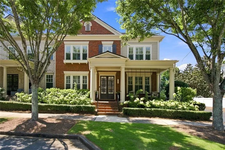 Brick and siding exterior with a covered porch, bay windows, and manicured landscaping