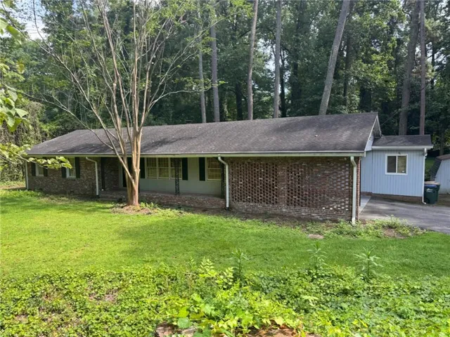 Brick and siding exterior with a dark shingle roof, featuring a front porch and an attached structure with a light-colored siding finish