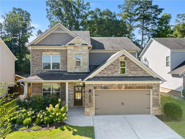 Two-story exterior with a brick and stone facade, covered front porch, an attached two-car garage, and a concrete driveway