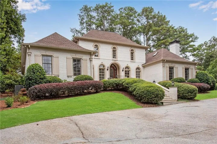 Stately two-story residence with a brick exterior, prominent arched entryway, and architectural shutters