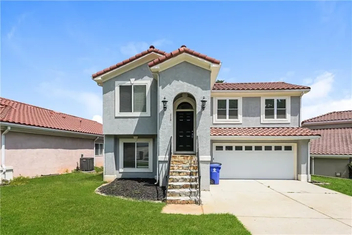 Mediterranean / spanish-style house with stucco siding, a garage, concrete driveway, and a front lawn