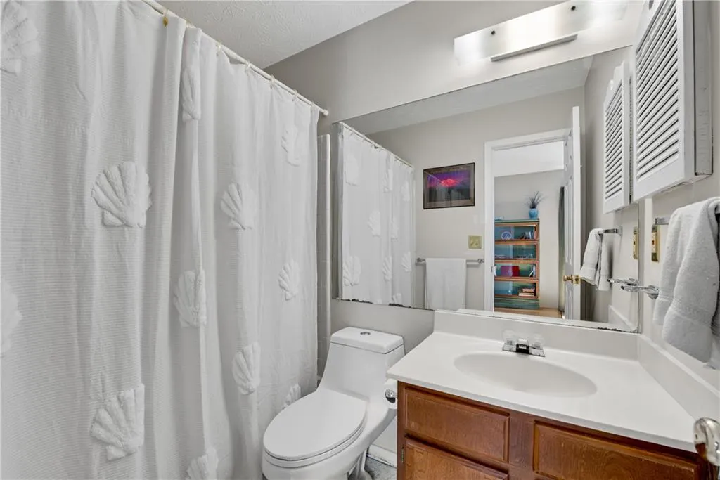 Bathroom featuring vanity, toilet, and a textured ceiling Bathroom featuring vanity, toilet, and a textured ceiling