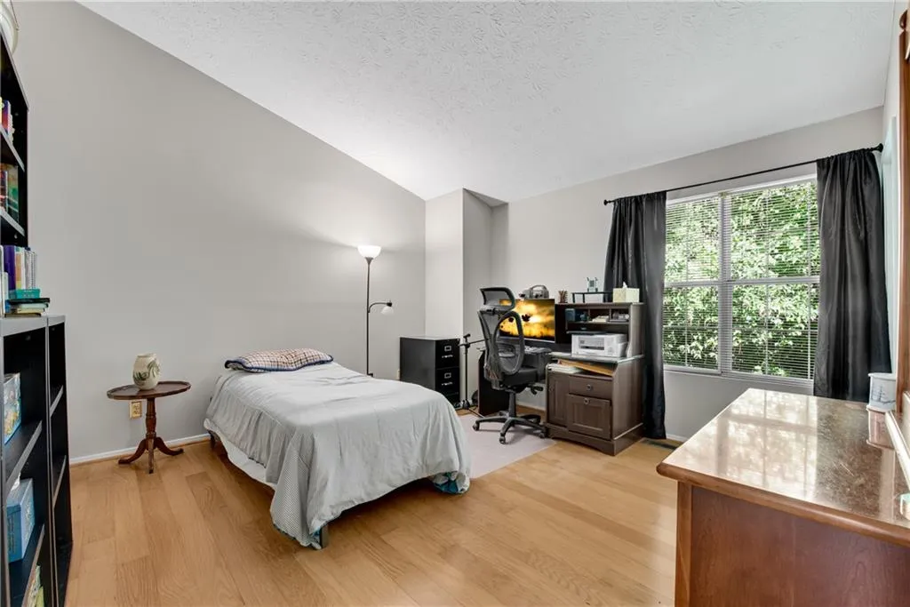 Bedroom with lofted ceiling, light wood-type flooring, and a textured ceiling Bedroom with lofted ceiling, light wood-type flooring, and a textured ceiling