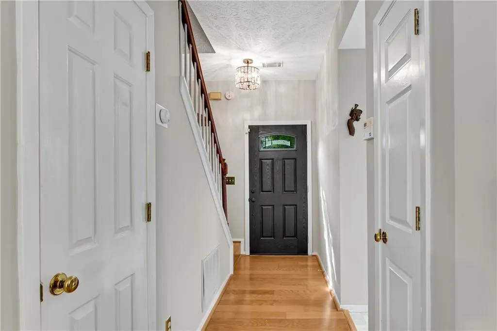Entryway featuring an inviting chandelier, light hardwood / wood-style floors, and a textured ceiling Entryway featuring an inviting chandelier, light hardwood / wood-style floors, and a textured ceiling