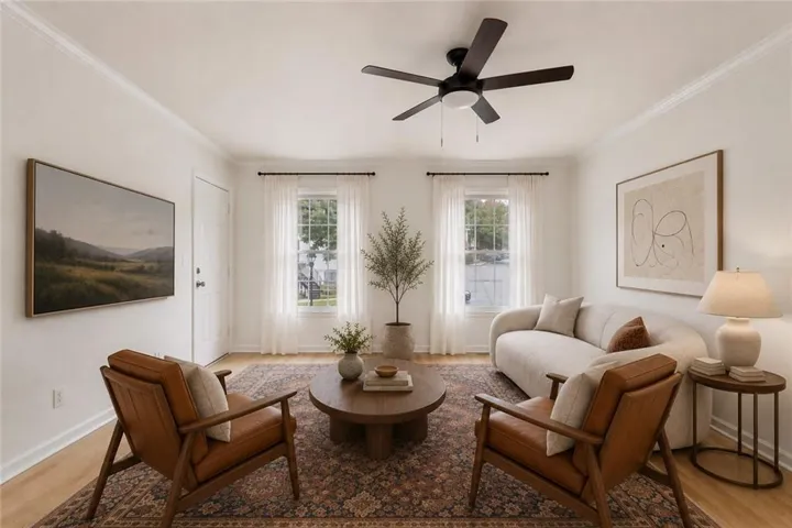 Bright living space with wood-finish flooring, two large windows, a ceiling fan, and crown molding