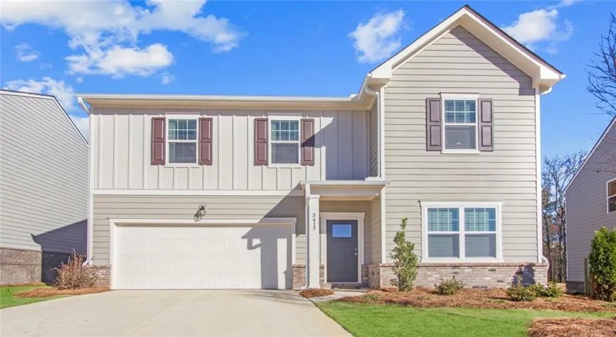 View of front of home featuring board and batten siding, an attached garage, concrete driveway, brick siding, and a front lawn