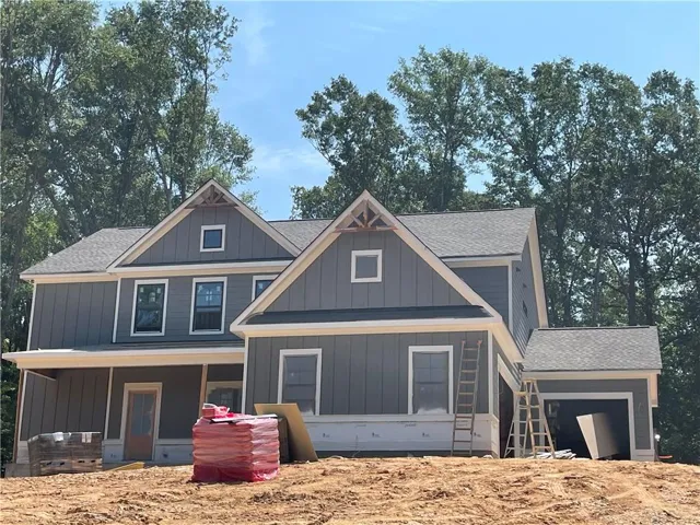 Two-story residence featuring grey vertical siding with white trim accents and a dark-toned roof