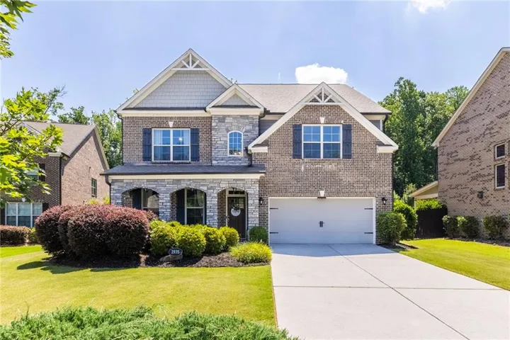Brick and stone facade with a gable roof, archway entry, and attached two-car garage