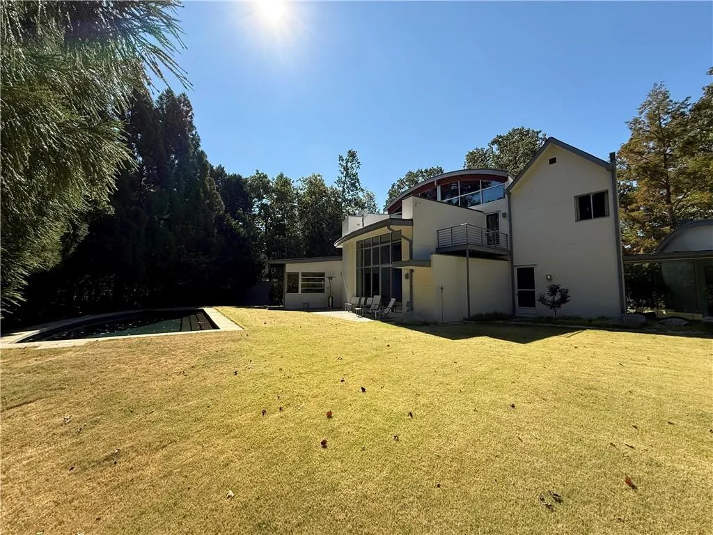 Rear view of property featuring a lawn and a balcony