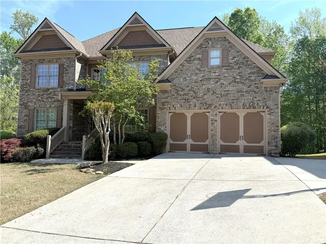 Craftsman-style home featuring concrete driveway, brick siding, a shingled roof, and an attached garage