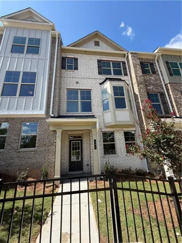 Three-story townhome with a light brick facade and vertical white siding accents