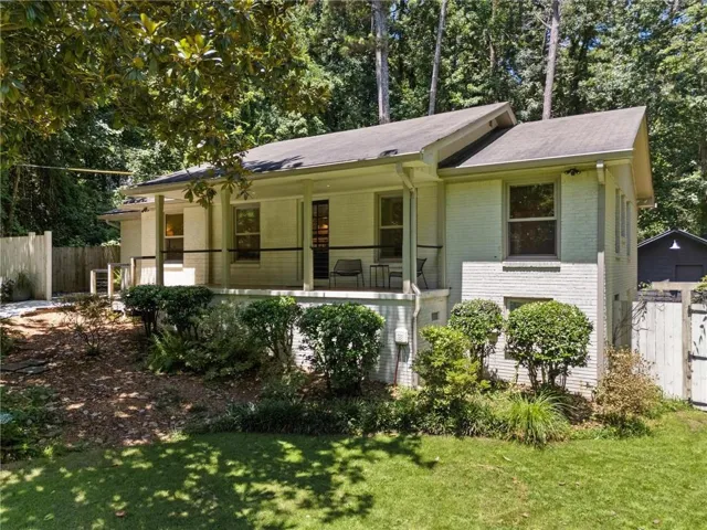 Brick exterior with a covered porch, established landscaping, and a fenced perimeter