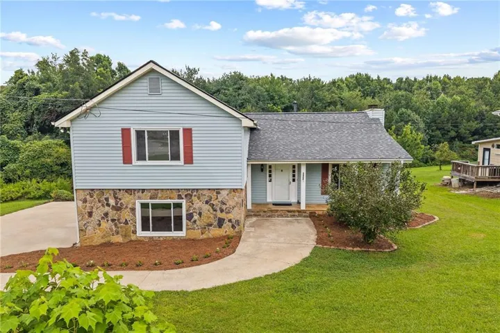 Light blue siding exterior with stone veneer accents, asphalt shingle roof, and a covered front entry