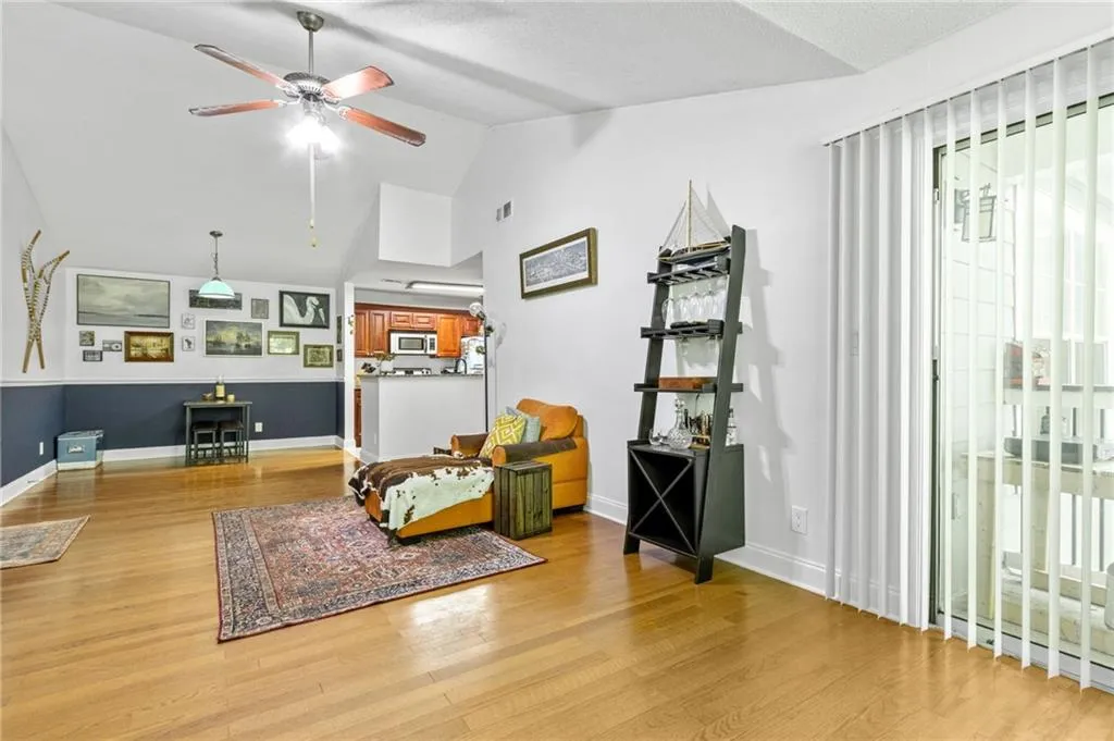 Living area with ceiling fan, vaulted ceiling, and light hardwood / wood-style flooring