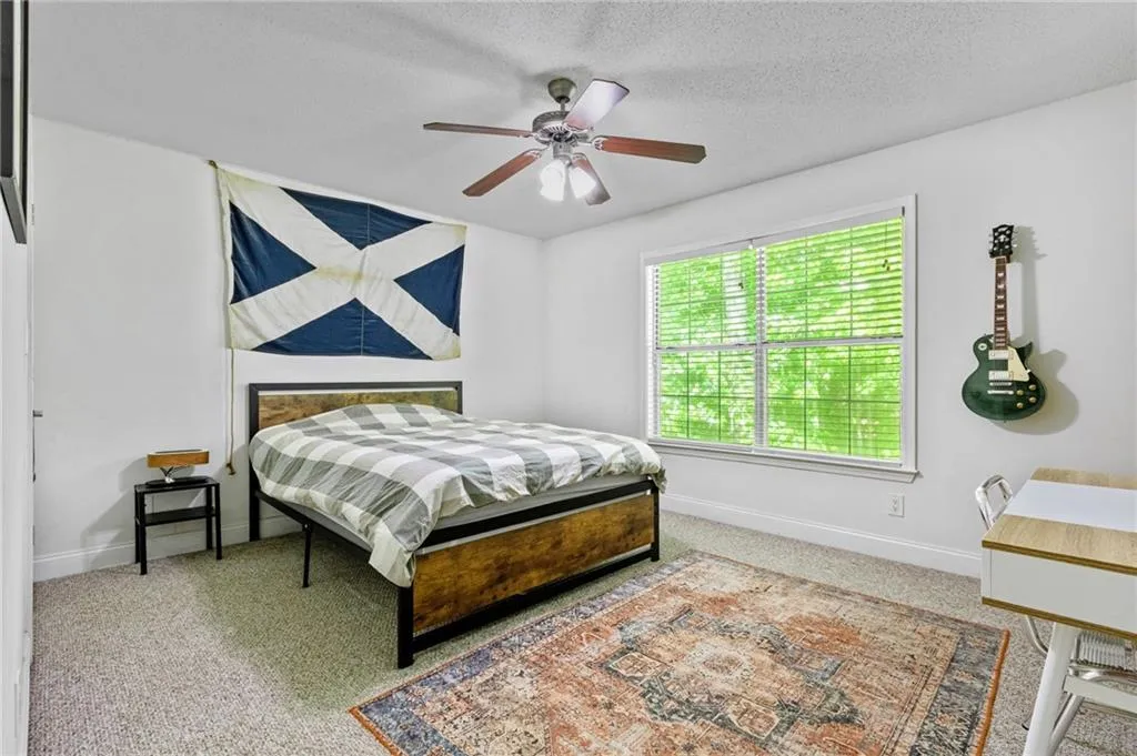 Carpeted bedroom with a textured ceiling and ceiling fan