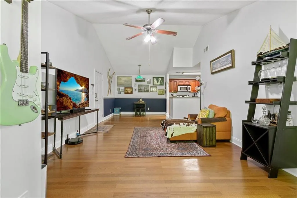 Living room with light wood-type flooring, vaulted ceiling, and ceiling fan