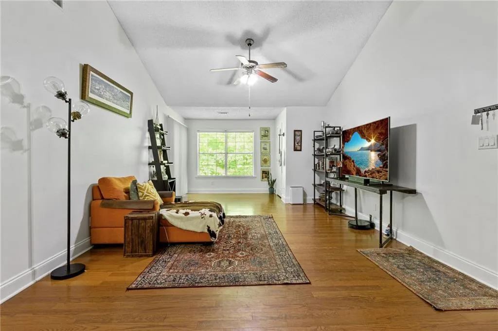 Living room with lofted ceiling, wood-type flooring, and ceiling fan
