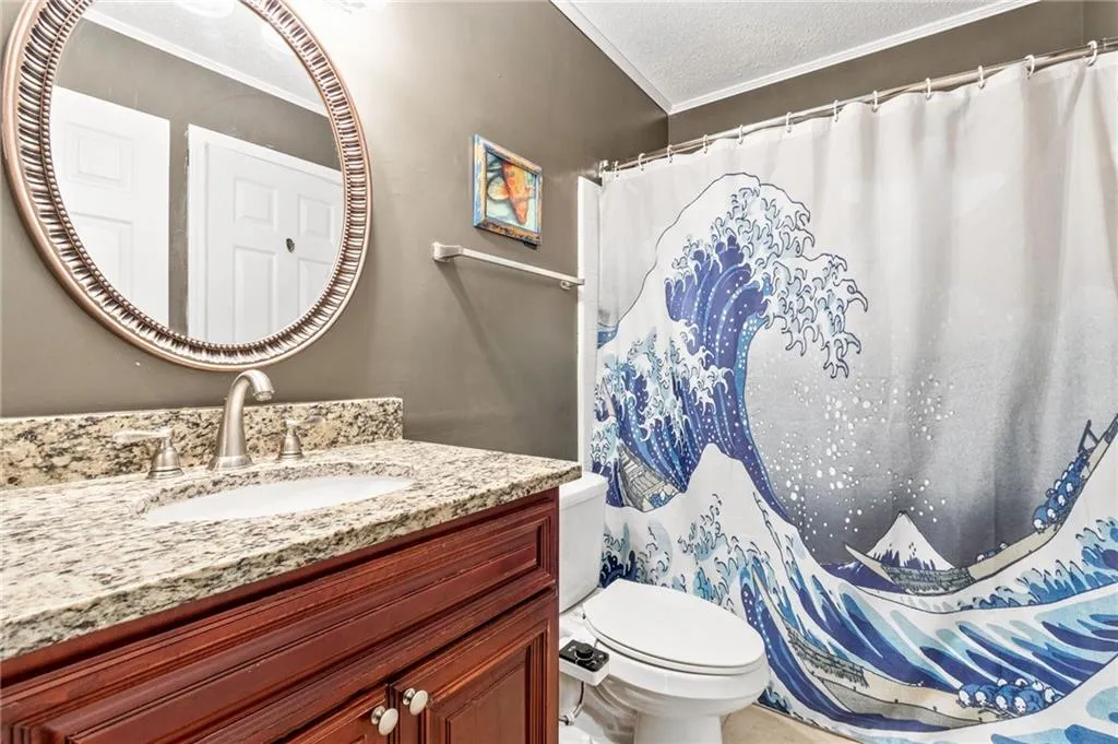 Bathroom featuring ornamental molding, a textured ceiling, toilet, and vanity