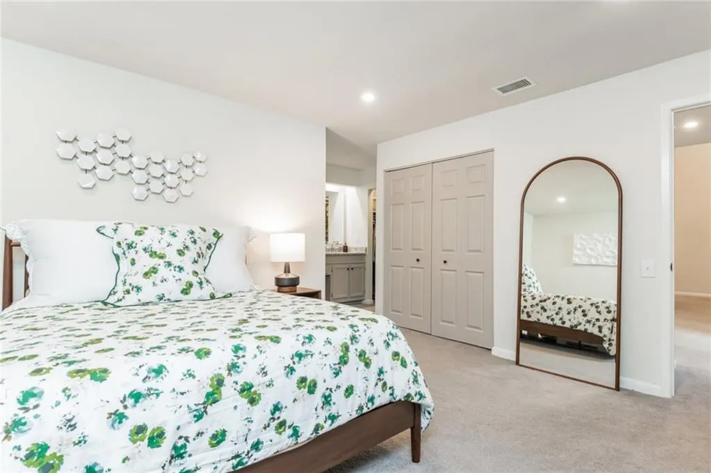 Bedroom with a closet, ensuite bathroom, and light carpet