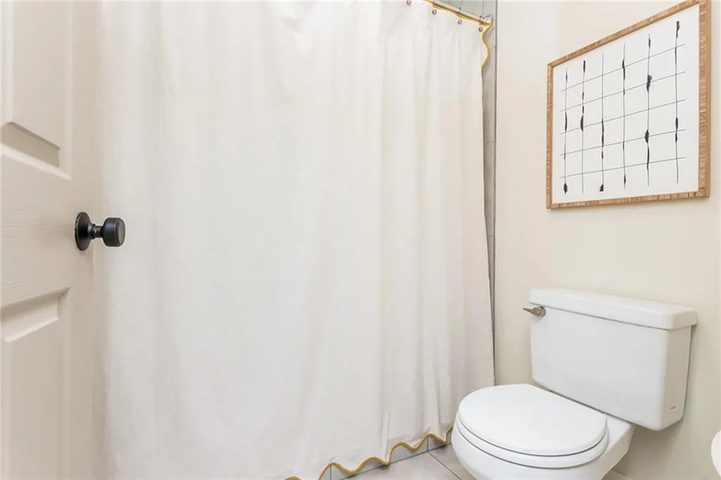 Bathroom with walk in shower, tile patterned floors, and toilet