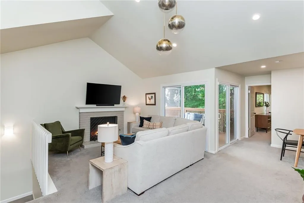 Carpeted living room featuring high vaulted ceiling and a fireplace
