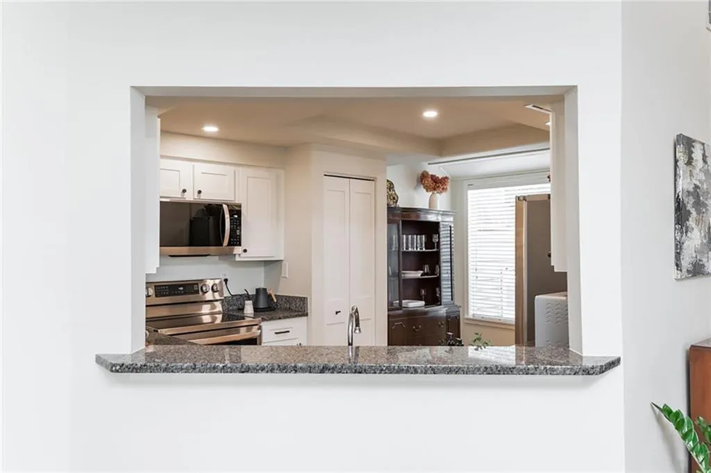 Kitchen featuring dark stone counters, washer / clothes dryer, stainless steel appliances, and white cabinets