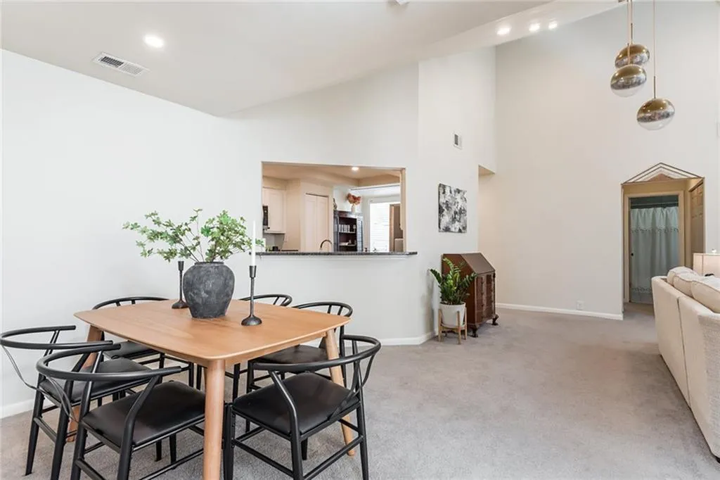 Carpeted dining space featuring high vaulted ceiling