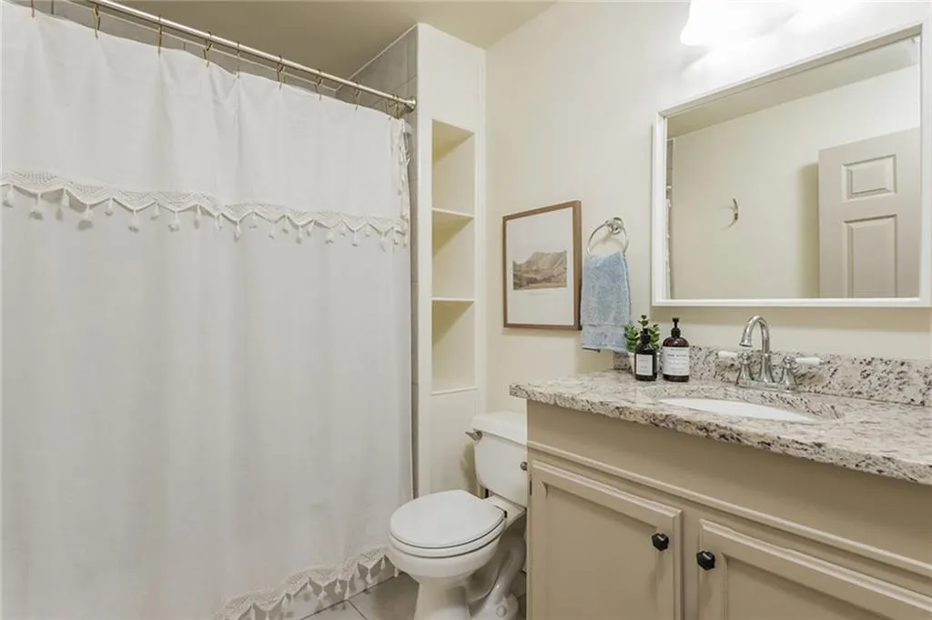 Bathroom with tile patterned floors, vanity, toilet, and curtained shower