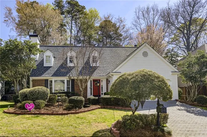 Cape cod home featuring brick siding, a front yard, driveway, and roof with shingles