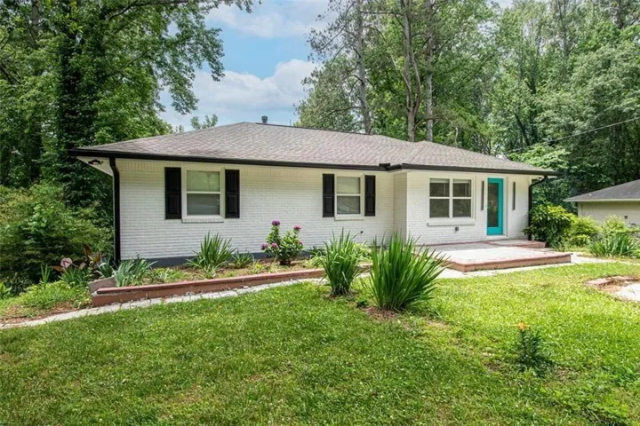 White brick exterior with black shutters and a turquoise entry door