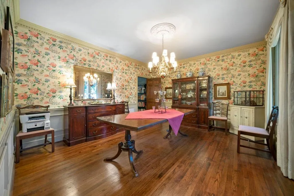 Dining space featuring a chandelier, ornamental molding, wallpapered walls, and dark wood-style flooring