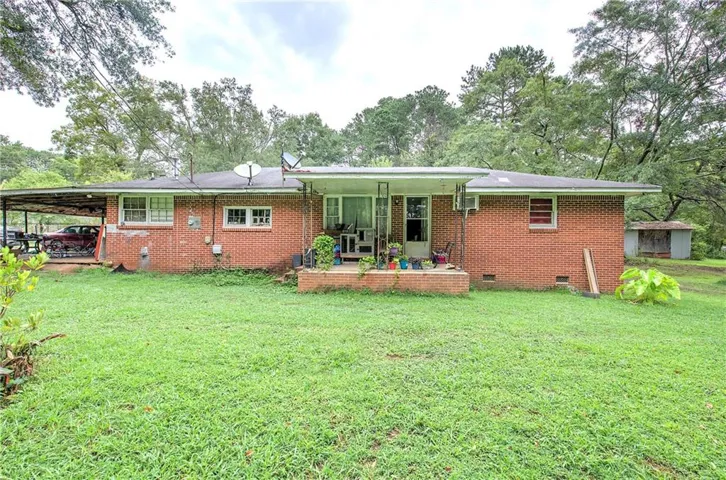 Brick exterior with a covered carport, rear patio, and a separate storage shed