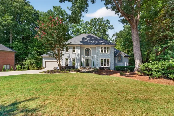 Stately two-story residence with a light-colored exterior and dark roof