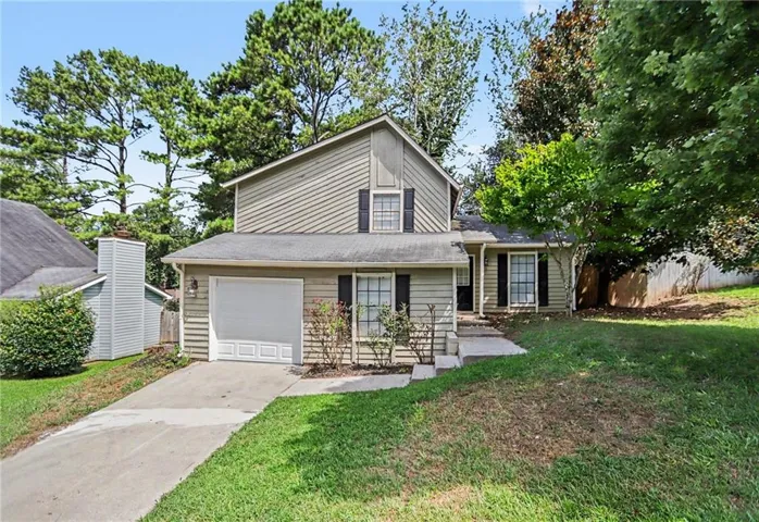 Two-story siding exterior with contrasting shutters, attached garage, and concrete driveway