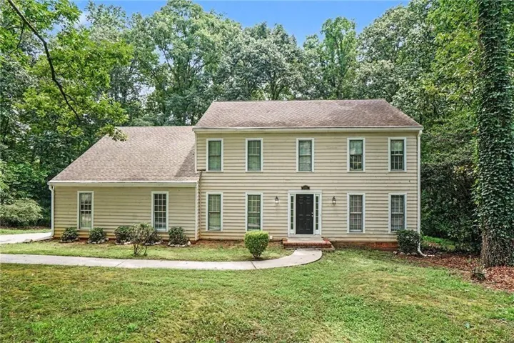 Traditional two-story residence featuring light-colored siding, a dark front door, and multiple windows with white trim
