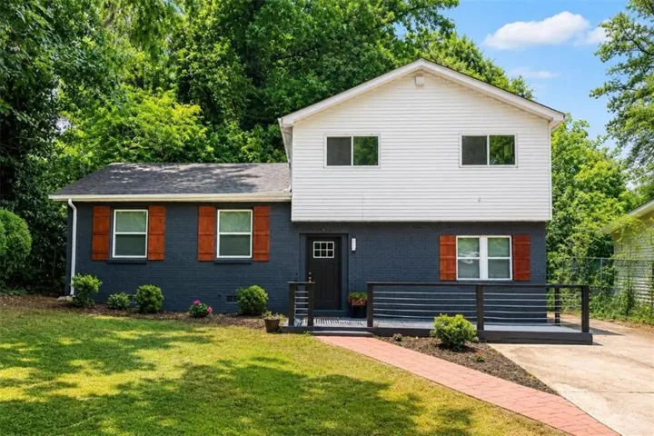 Split-level residence featuring a dark-painted brick facade and white siding upper level