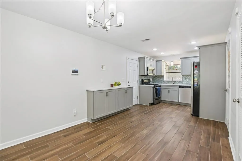 Kitchen with appliances with stainless steel finishes, gray cabinets, dark wood-style floors, a chandelier, and recessed lighting