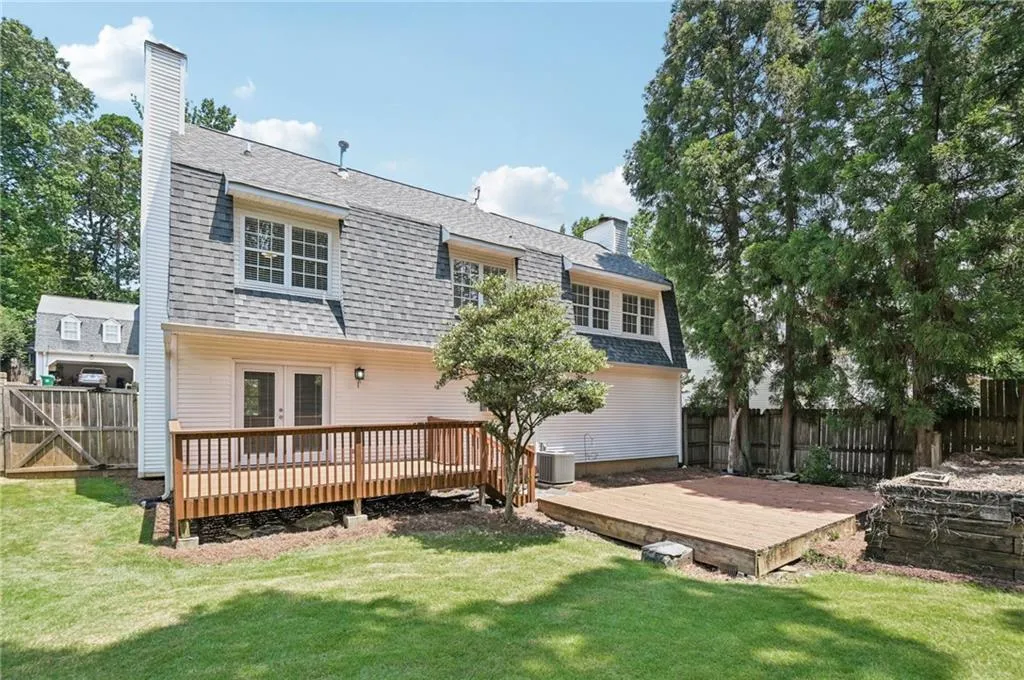 Back of property featuring a chimney, a wooden deck, and a fenced backyard