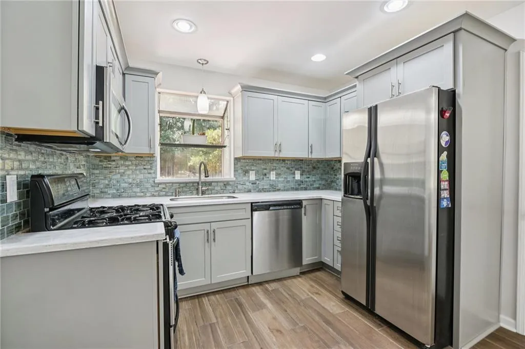 Kitchen with stainless steel appliances, gray cabinets, light wood-type flooring, and recessed lighting