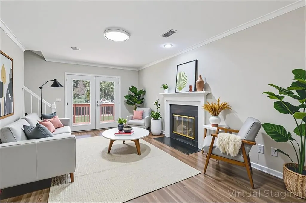 Living room featuring ornamental molding, wood finished floors, french doors, a glass covered fireplace, and stairs