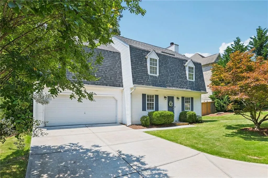 Dutch colonial featuring roof with shingles, driveway, a gambrel roof, a chimney, and an attached garage