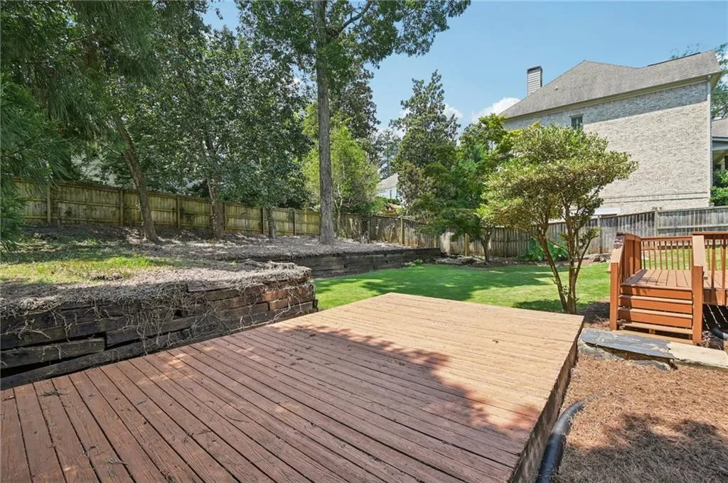 Wooden terrace with a fenced backyard