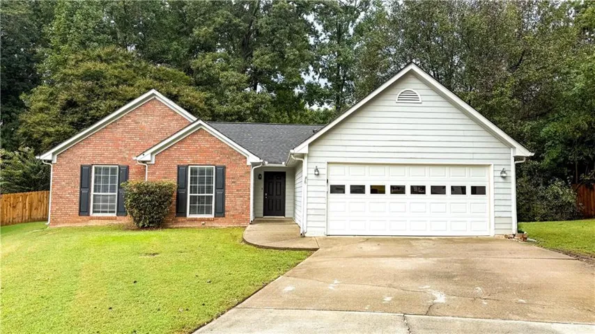 Brick and siding exterior with dark shutters, an attached two-car garage, and a concrete driveway