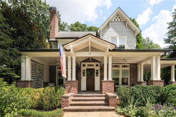 Charming brick Colonial home featuring a welcoming covered front porch with white columns and exposed beam detailing