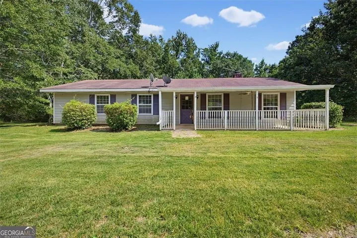 Single-story residence with a covered front porch featuring white railings, a purple entry door, and exterior shutters