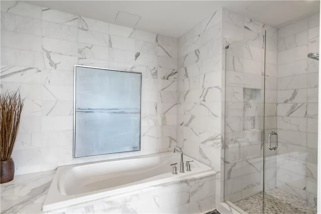 Full bathroom featuring a bath, a marble finish shower, and tile walls