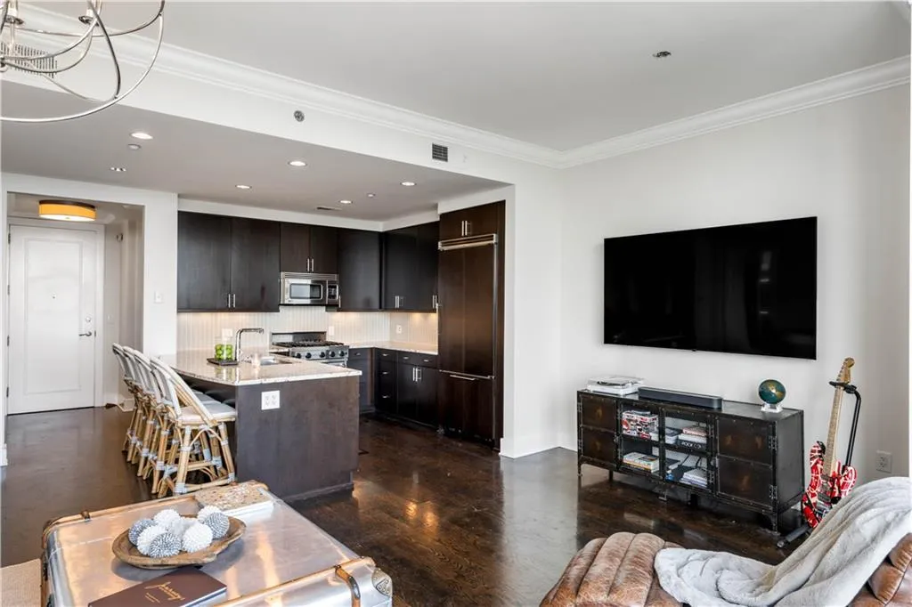 Kitchen with tasteful backsplash, a breakfast bar, appliances with stainless steel finishes, dark wood-style floors, and light stone countertops