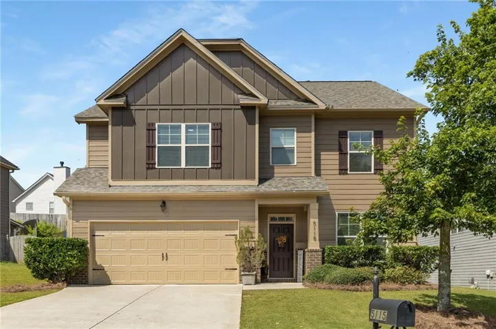 Two-story residence featuring a two-car garage, brick accents, and a covered entry