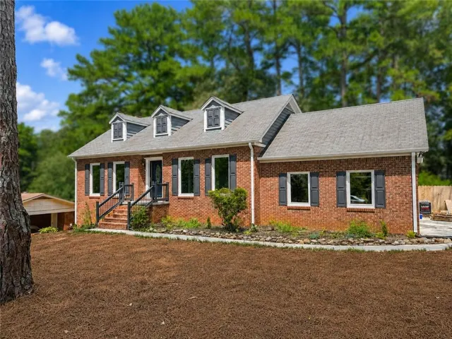 Brick exterior with dormer windows, a covered entry, and black shutters