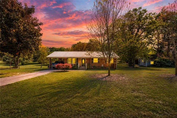 Ranch-style residence featuring a metal roof, an extended covered carport, and multiple large windows